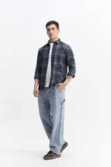 Camisa de manga larga confeccionada en viyela de algodón con diseño de cuadros en tonos azul y verde. Presenta cierre frontal con botones, cuello clásico y bolsillo en el pecho.