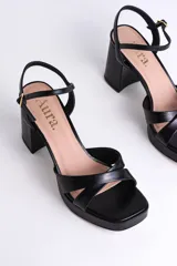Sandalias negras de cuero sintético con plataforma y tacón cuadrado. Presentan tiras cruzadas en el empeine y pulsera con hebilla al tobillo.