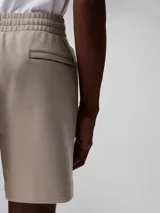 Short de jogging color beige, de tejido de punto de algodón acanalado, con cintura elástica, bolsillos laterales y trasero. Presenta logo CK bordado en blanco en la pierna izquierda.