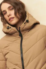 Campera puffer color beige, de nylon, con capucha, cierre frontal, elástico en la cintura y doble bolsillo.