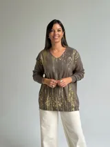 Sweater de punto color verde seco con estampado de salpicaduras en color dorado, cuello en V y mangas largas.