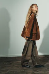Blazer de gamuza color marrón con cuello solapa, manga larga con hombreras y cierre frontal con botones. Incluye bolsillos con solapa en el delantero, bolsillo de vivo en el pecho y cinturón de lazada en el mismo material.