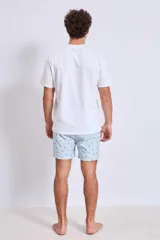 Short de baño de corte clásico en color celeste claro con estampado de pequeñas aves en tono oscuro. Cuenta con cintura elástica y un pequeño parche decorativo en el ruedo.