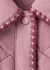 Chaqueta oversize acolchada de color rosado con diseño pespuntado en zigzag, cuello camisero, manga larga, bolsillos delanteros de parche y ribetes en contraste.