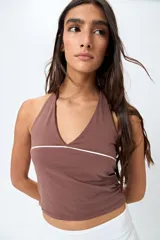 Top halter negro con escote en V y detalle de vivo blanco horizontal. Presenta un diseño ajustado al cuerpo y espalda descubierta con tiras regulables.