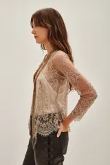 Saco de encaje con diseño floral y detalles bordados en hilo dorado. Presenta mangas tres cuartos, escote en V y bordes con terminación de puntilla. El diseño es abierto al frente con una estructura delicada y elegante.