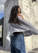 Poncho de hilo liviano en color gris claro, con cuello alto y diseño de caída fluida y holgada. Es una prenda versátil ideal para media estación.