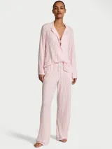 Pijama largo de modal suave con diseño de rayas verticales en tonos rosado y blanco, compuesto por una camisa de manga larga con botones al frente y bolsillo en el pecho, y un pantalón con cintura elástica y cordón ajustable.