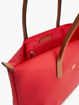 Cartera tote Tommy Hilfiger de nailon rojo, con cierre de cremallera, asas superiores de cuero sintético tostado y monograma metálico TH en la parte delantera.