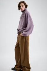 Jersey de punto con cuello alto y cierre frontal de cremallera metálica, de manga larga con puños ajustados y diseño holgado.