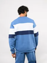 Buzo de cuello redondo confeccionado en felpa, con diseño de bloques de color en azul, rojo y blanco. Presenta el logo de Umbro y el escudo del Club Nacional de Football bordados en el frente.