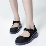 Mocasín estilo Mary Jane de la marca Melissa, modelo June Ad, confeccionado en material sintético negro con acabado brillante. Cuenta con tira ajustable en el empeine con hebilla gruesa, puntera reforzada en tono mate y suela translúcida de goma con diseño chunky.