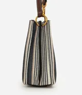 Cartera bucket pequeña de Satinato con diseño de rayas verticales en tonos blanco, azul marino y beige, confeccionada en tejido estructurado. Cuenta con asa de mano fija, asa larga desmontable de cuero sintético marrón, detalles de herrajes metálicos dorados, argolla metálica colgante en el frente y cierre superior.