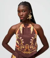 Blusa halter color marrón de viscosa, con diseño sin mangas, cuello halter con atadura posterior y estampa tropical inspirada en pañuelo con detalles en tonos dorados y naranjas.