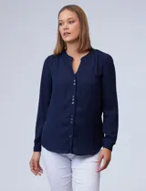 Blusa azul marino de gasa marca Zac & Rachel, con cuello a la base y escote en V. Manga larga regulable con presilla y botón. Aplique de puntilla en hombros.