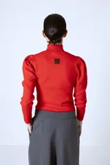 Polera de punto color rojo, con cuello alto y mangas largas con detalle de frunces en los hombros.