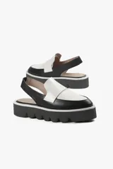 Mocasín slingback de cuero negro con detalle blanco en el empeine y base con plataforma dentada.
