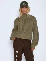 Sweater de punto grueso con cuello alto, mangas largas raglán y puños acanalados. Presenta un diseño de textura acanalada y corte holgado.