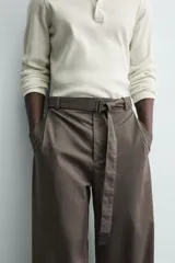 Pantalón de corte wide fit confeccionado en tejido con algodón. Presenta pliegues frontales, cintura ajustable con cinturón integrado, bolsillos laterales y bolsillos traseros de vivo. Cierre frontal con cremallera y botón.