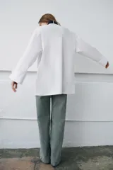 Camisa oversize de algodón con cuello redondo y solapa, manga larga con puño con vuelta y hombro caído. Presenta detalle de tablas en el delantero, cierre frontal con botones ocultos y corbata a contraste incluida.