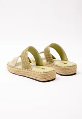 Sandalia con doble tira en el empeine, una de cuero color tostado y otra tejida en rafia. Plataforma de yute de 3.5 cm de alto.