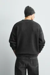 Jersey de corte relajado confeccionado en tejido de algodón con efecto lavado. Presenta cuello redondo, manga larga, acabados en rib y un bordado a tono en el delantero con diseño abstracto.