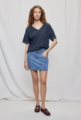 Falda de denim blanca de corte recto con bolsillos delanteros aplicados, costuras pespunteadas a contratono y cierre frontal con botón y cremallera.