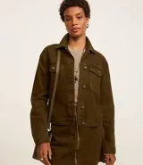 Campera trucker color verde oliva confeccionada en sarga de algodón, con cuello inglés, manga larga, bolsillos delanteros con solapa y abotonado delantero.