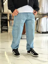Pantalón cargo de jean azul claro, con bolsillos laterales tipo cargo en las piernas y bolsillos frontales aplicados, de corte ancho y holgado.