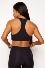 Top deportivo negro con cierre frontal, espalda cruzada y logo estampado en el pecho. Cuenta con abertura interna para copas removibles.