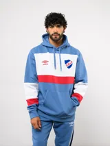 Canguro con capucha de Umbro del Club Nacional de Football, con diseño de bloques de color en azul, blanco y rojo. Cuenta con bolsillo frontal tipo canguro, cordones ajustables en la capucha y logo de la marca junto al escudo del club en el pecho.
