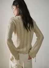 Buzo de punto medio de algodón color beige con diseño recto, detalles calados con patrón en zigzag, cuello redondo y manga larga.