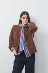 Cardigan de textura suave y efecto fluffy, color beige, con cuello redondo, cierre frontal con botones y puños acanalados.