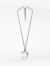 Collar con cordón largo ajustable de color negro y un dije metálico grande y brillante con forma de letra 'C' o media luna. El ajuste del cordón es tipo bolo con terminales metálicos grabados.