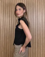 Musculosa a rayas verdes y blancas, con cuello alto fruncido, cierre frontal con botones y volados en los hombros.