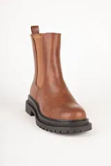 Bota Chelsea de cuero sintético color negro, con elástico lateral, puntera redondeada con detalle de perforaciones y suela track.