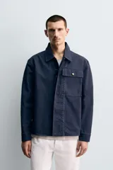 Sobrecamisa de corte regular confeccionada en tejido de algodón con estructura canvas, color negro. Presenta cuello solapa, manga larga con puño abotonado, un bolsillo frontal de plastrón y cierre frontal con botonadura oculta.