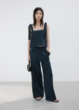 Pantalón de mezclilla azul oscuro, con silueta wide leg, tiro alto y pretina con cordón ajustable.