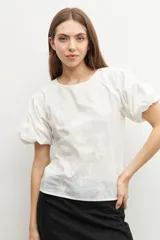 Blusa amarilla con estampado floral, mangas cortas abullonadas y cuello redondo.