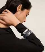 Set de dos brazaletes rígidos abiertos, uno plateado liso y otro azul traslúcido.