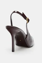 Zapato destalonado de tacón fino alto, con diseño en punta y acabado texturizado efecto cocodrilo. Cuenta con tira trasera ajustable mediante hebilla metálica.