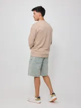 Sweater color arena con logo Rusty estampado en el pecho, de corte regular fit.