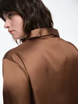 Camisa de dormir de satén con cuello solapa, cierre frontal con botones y mangas largas. Presenta un corte holgado y fluido.