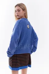 Cardigan de tejido de punto color marrón, con cuello solapa, cierre frontal de cremallera y diseño de trenzas. Cuenta con puños y dobladillo en rib elástico y un pequeño bordado en el pecho.