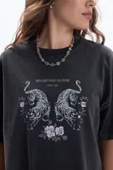 Remera negra de manga corta, corte holgado y diseño boxy. Presenta un estampado frontal de dos tigres enfrentados rodeados de flores, con la frase "BRILLENT POUR TOUJOURS PARIS, 1986".