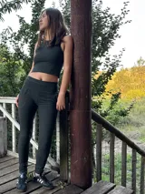 Conjunto deportivo de dos piezas en color verde oscuro, compuesto por un top reversible con escote redondo y un pantalón slim de tiro alto con faja ancha y bolsillos.