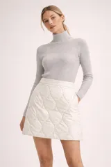 Falda corta de diseño acolchado con patrón de rombos, color blanco, de corte en A y cintura alta.