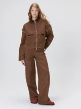 Campera de denim a rayas verticales con cuello de pana en color bordó. Presenta cierre frontal, mangas desmontables con cierre en los hombros, canesú en el pecho y bolsillos de parche cuadrados.