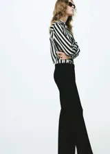 Camisa de manga larga con estampado de rayas verticales blancas y negras, cuello camisero, cierre frontal con botones y tejido semitransparente.