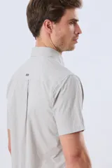 Camisa de manga corta de algodón en color celeste con microdiseño geométrico a cuadros, cuello camisero y bolsillo frontal con logo bordado.